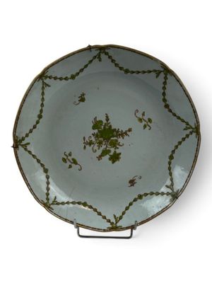 a green and white plate on a stand on a white surface