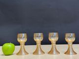 four wine glasses sitting next to an apple on a table