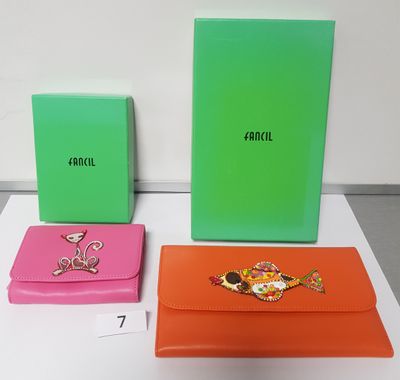 three different colored clutches are sitting on top of a table