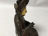 a statue of a woman sitting on a rock with a crown on her head