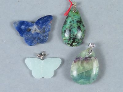 trois pierres vertes, bleues et blanches, accompagnées d'un pendentif en forme de papillon