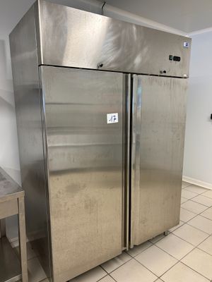 two stainless steel refrigerators in a kitchen with tile flooring