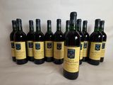 six bottles of wine are lined up on a white surface