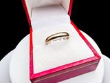 a gold ring in a red box on a white plate