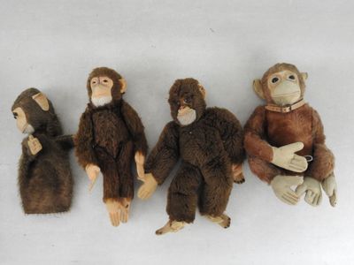 trois singes en peluche assis les uns à côté des autres sur une surface blanche