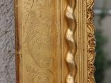 a gold framed mirror with a decorative design on it