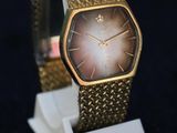 a gold watch on a white stand on a black background