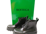 a pair of black boots that are next to a box of bottega
