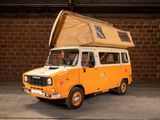 an orange van with a brown roof parked in front of a brick wall