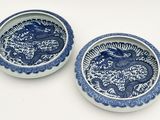 deux assiettes bleues et blanches ornées de motifs de dragons sur fond blanc