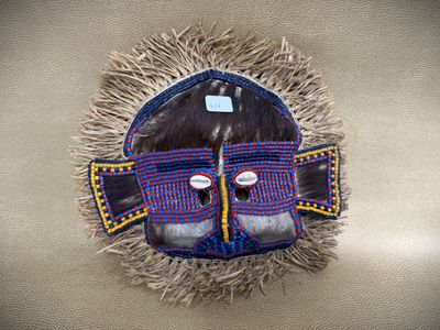 a close up of a mask with feathers on a wall