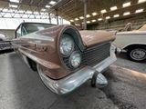 a brown and white car in a garage with other cars