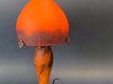 une lampe de table orange avec un cordon qui y est attaché, posée sur une surface grise
