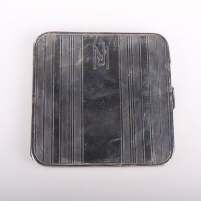un vieil étui en argent orné d'un monogramme sur fond blanc