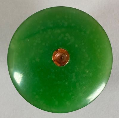 a green glass object with a brown button on it