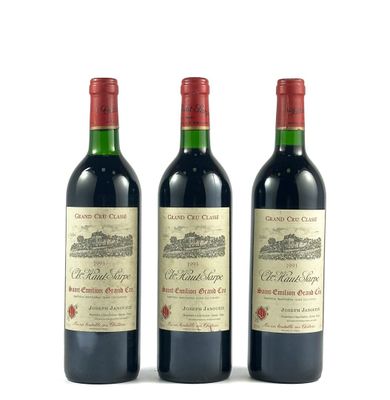 trois bouteilles de vin rouge posées l'une à côté de l'autre sur une surface blanche