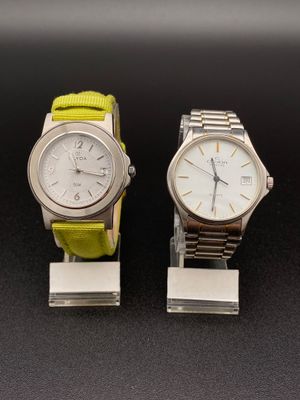 une paire de montres avec des bracelets verts, exposées sur un fond noir