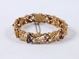 gold bracelet with garnetts and a chain on a white background