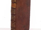 an old brown book with gold trim sitting on top of a white table