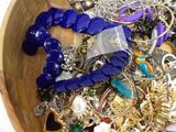 a wooden bowl filled with lots of jewelry on a table