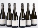 six bottles of wine are lined up in a row on a white surface