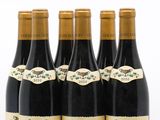 six bottles of wine are lined up in a row on a white surface