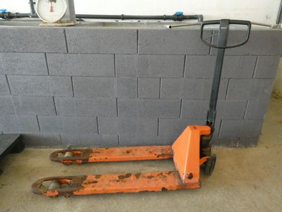 an orange forklift sitting in front of a brick wall