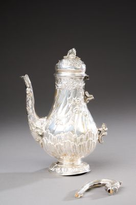 une théière en argent et une cuillère en argent posées sur une table