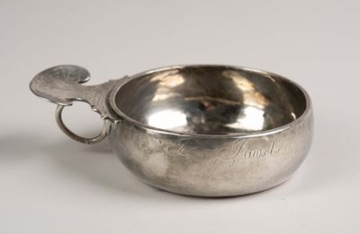 a silver bowl with a handle on a white surface