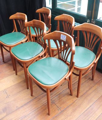 six chaises en bois avec des assises en cuir vert, placées devant une fenêtre