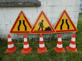 trois panneaux de signalisation gisant au sol à côté de cônes orange et blancs