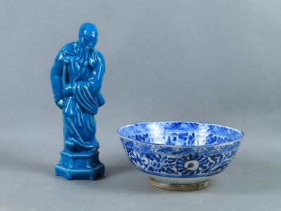a blue and white bowl with a statue next to it