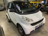 a small white smart car parked in a garage