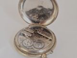 a silver pocket watch sitting on a white surface