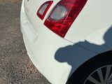 a white car parked in a parking lot next to a brick wall