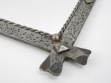 a metal cross with a chain around it on a white surface