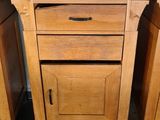 two wooden cabinets and a black counter top on the floor