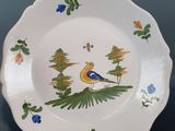 a plate with a bird painted on it sitting on a table