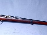 Un vieux fusil est posé sur une surface blanche, sur fond bleu.