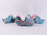 two blue clogs with colorful flowers on them sitting on a white surface