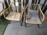 three wicker chairs with cushions on them in front of a wall