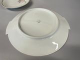 a white plate with a flower design on it next to a plate with a flower design on it