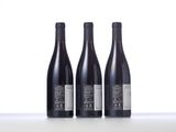 three bottles of wine are lined up on a table