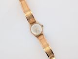 une image d'une montre-bracelet en or sur une surface blanche