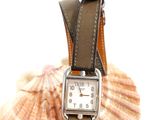 a close up of a watch with a shell in the background