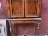 une armoire en bois sur le dessus de laquelle est accrochée une peinture