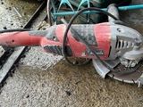 une meuleuse électrique rouge et noire posée par terre