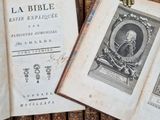un vieux livre surmonté d'une statue représentant une main, à côté d'une pile de vieux livres
