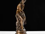 a bronze statue of a woman sitting on a rock