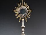 an image of a silver and gold cross on a pedestal